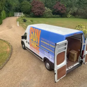 A sunshine removal van with the back doors open, on a large gravel driveway.