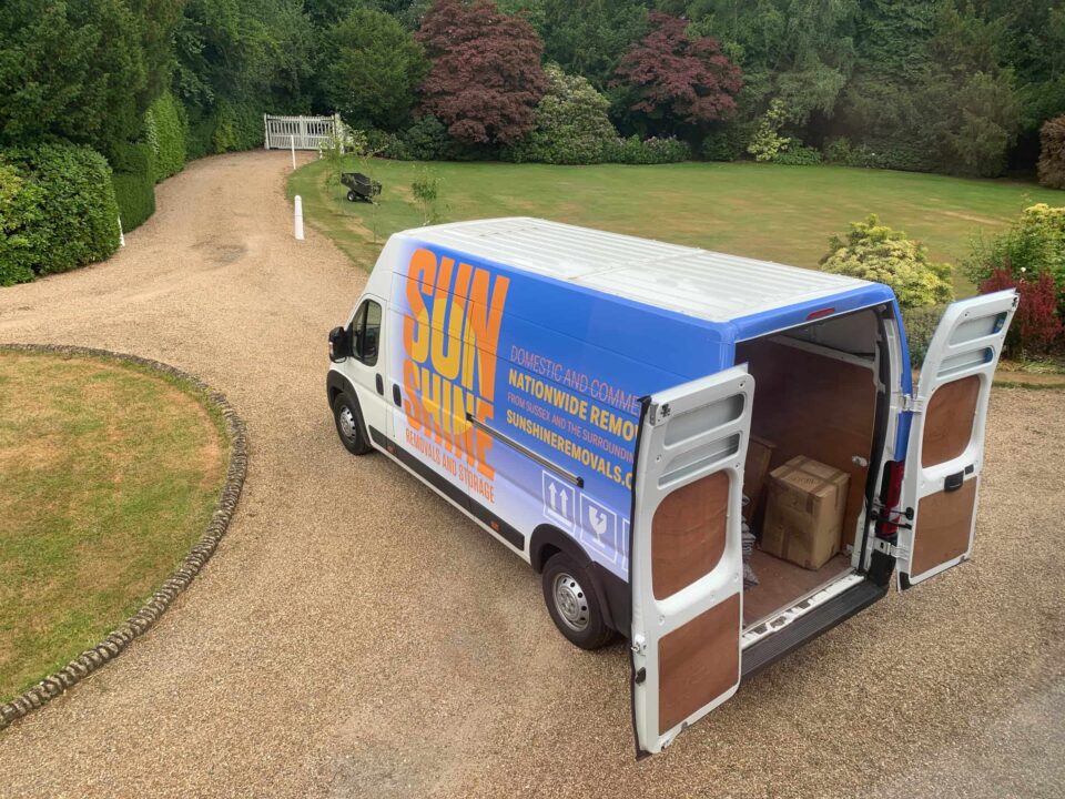 A sunshine removal van with the back doors open, on a large gravel driveway.