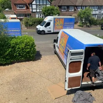 View from a house window, looking outside at three Sunshine Removals vans in the driveway and street.